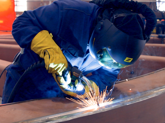 Welder performing MIG MAG welding in an industrial fabrication facility