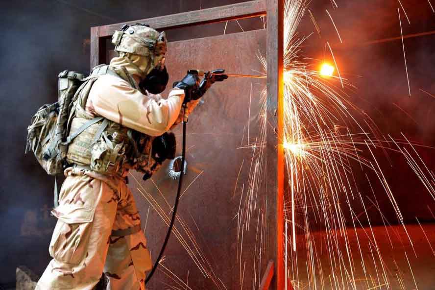 Firefighter cutting through a metal door with a SLICE exothermic cutting torch during a fire and rescue operation