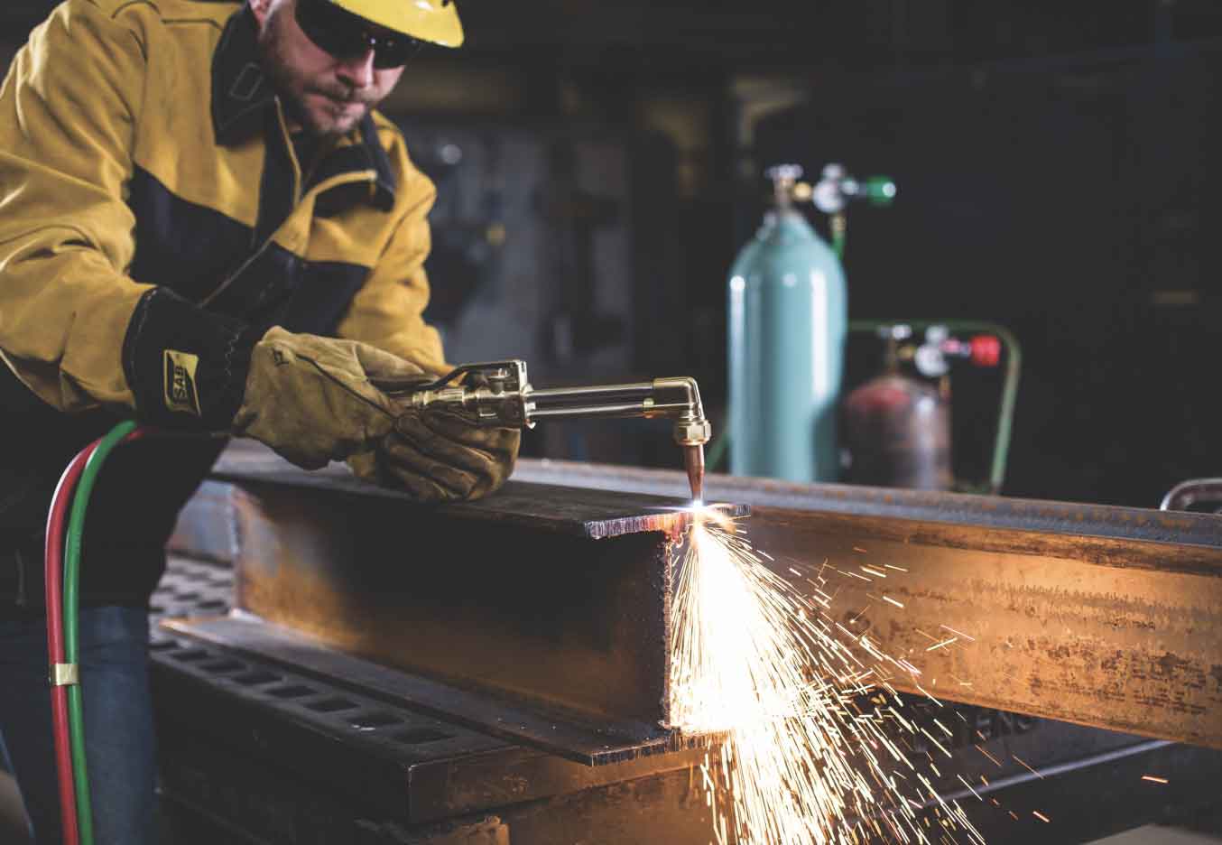 Welder in action with EDGE 2.0 regulators on gas cylinders in the background