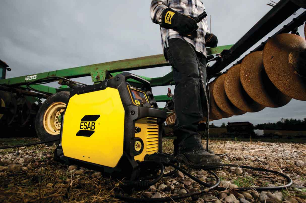 Welder with ESAB Rebel multi-process welder and farm machinery in the background