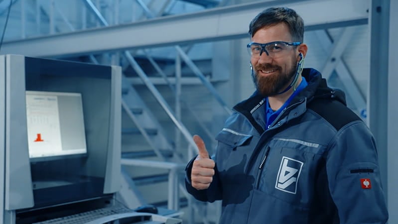 Operator at a terminal in PPE, smiling with thumbs up