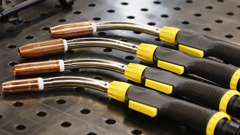 Senior product manager demonstrating ESAB Tweco MIG welding gun in product showcase environment.