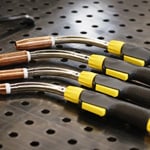 Close-up of MIG welding with Tweco gun producing arc and sparks during metal fabrication.